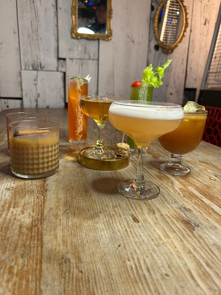 Signature cocktails on a rustic wooden table at Inmigrante