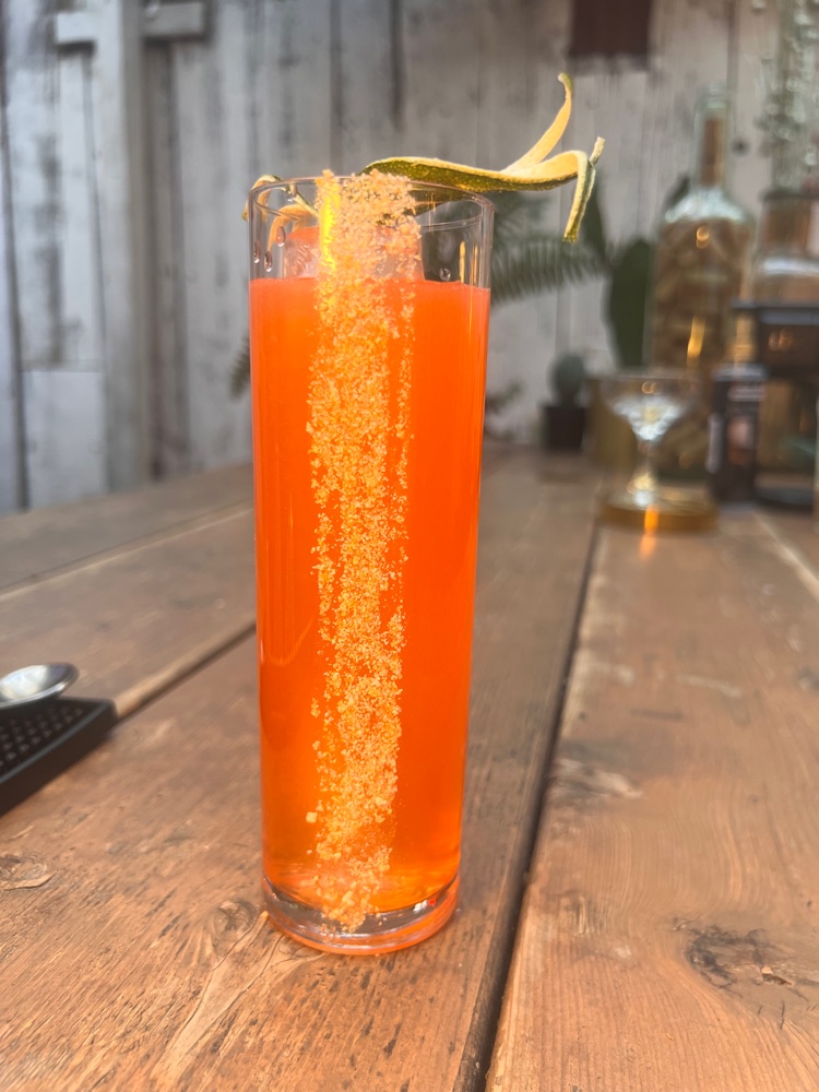 Vibrant orange Paloma cocktail on the Inmigrante patio