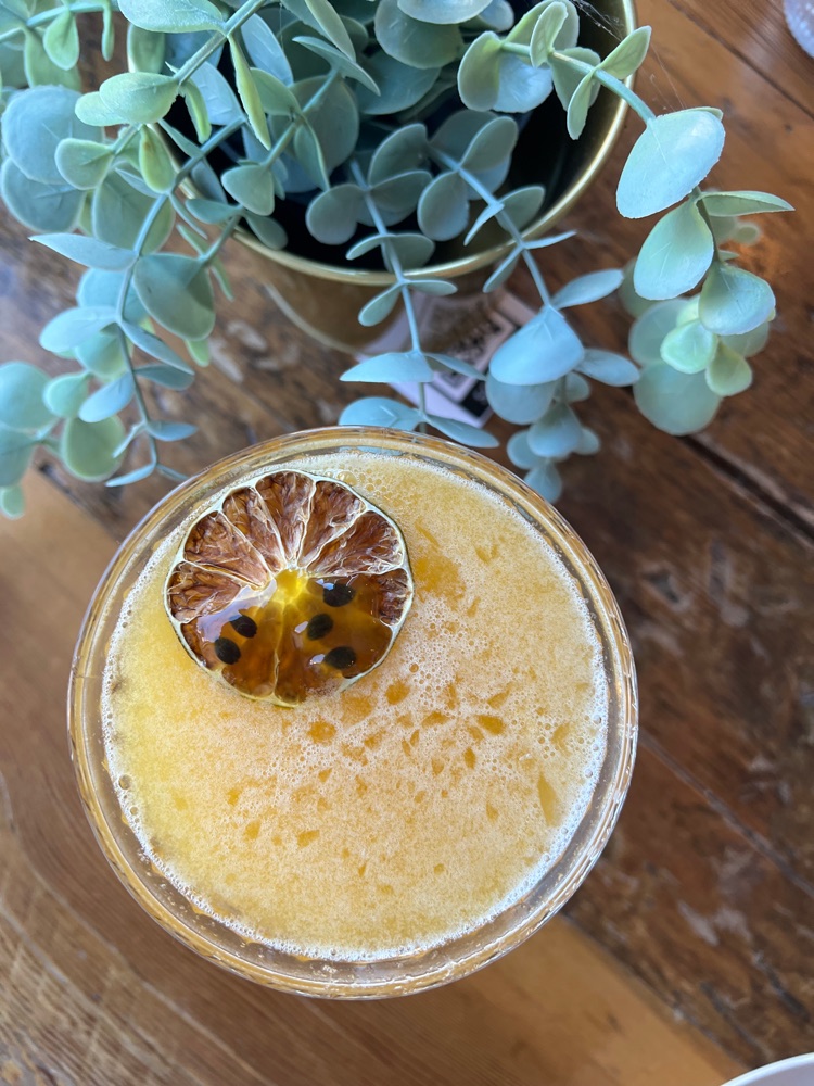 Passion fruit cocktail garnished with dried citrus, viewed from above